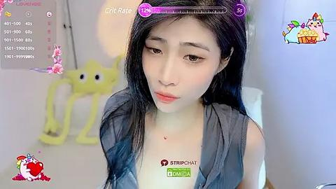 Media: A video of a young Asian woman with long black hair, fair skin, and a petite frame, wearing a sleeveless denim top, sitting in a bright, colorful room with a yellow toy spider and a calendar.