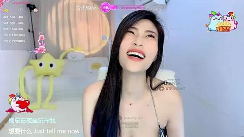 Media: Video of an Asian woman with long black hair, wearing a black tank top, smiling. Background features a yellow robot and a white wall.