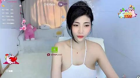 Media: A video of an East Asian woman with pale skin, dark hair, and a slender physique, wearing a white halter top. The background features a pink plush toy and a white bed, with virtual overlays.