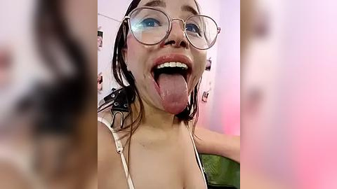 Media: A close-up video of a young Asian woman with glasses and wet hair, sticking her tongue out playfully, wearing a white top.