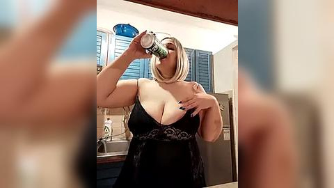 Media: Video of a blonde, curvy woman with large breasts, wearing a black lace camisole, drinking from a bottle in a modern kitchen with blue shutters.