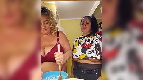 Media: Video of two women, one in a red bra and the other in a Mickey Mouse T-shirt, stirring a bowl of blue batter. Background features yellow walls and a blurred person in the foreground.