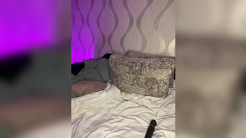 Media: A video of a messy bedroom with a person sleeping on a bed, surrounded by white sheets and pillows, under purple and blue LED lighting.