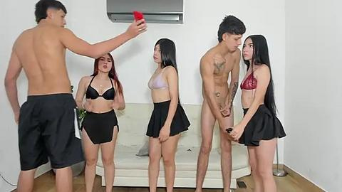 Media: Video of five young adults in a living room: two shirtless men, three women in lingerie, one man holding a red phone.