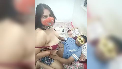 Media: Video: A topless, fair-skinned woman with large breasts and a red mask, sitting on a blue-shirted man with a yellow mask on a bed with patterned sheets.