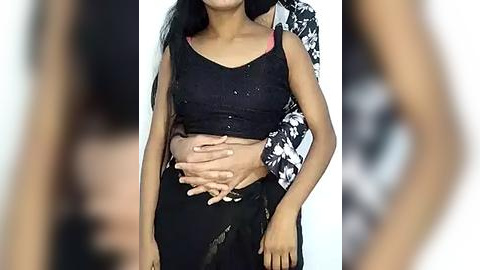 Media: Video of a pregnant woman with medium brown skin, wearing a black tank top and black pants, with a baby bump visible.