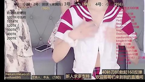 Media: A screenshot of a live-streaming video shows a woman in a white and red sailor outfit, seated on a gray couch. The background features Chinese text and chat messages.