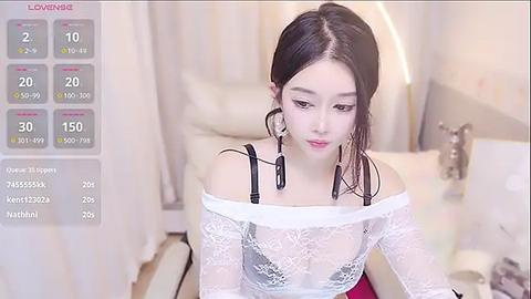 Media: A video of a young East Asian woman with pale skin, long black hair, and a white lace dress, sitting on a bed in a softly lit room.