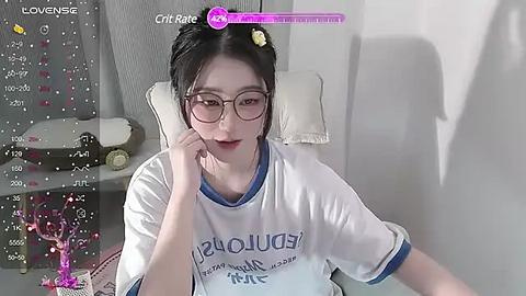 Media: A video of an East Asian woman with glasses, black hair, wearing a white t-shirt, sitting in a chair, reading a book. Background includes a cat toy and a calendar.