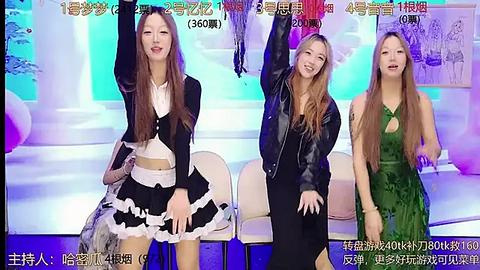 Media: Video of three Asian women, one in a black maid outfit, another in a black leather jacket, and the third in a green dress, all smiling and raising their arms in a lively studio.