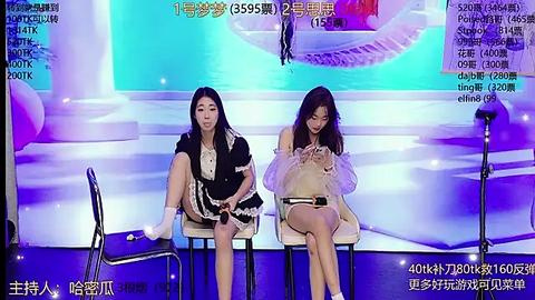 Media: Video of two Asian women in modern dresses, sitting on white stools in a bright, modern room. Background shows a stage with digital screens and stage lights.