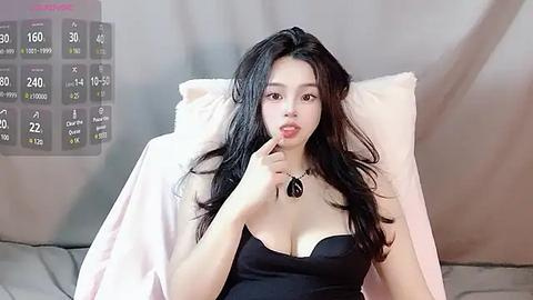 Media: A video of an Asian woman with long black hair, wearing a black dress, sitting on a white couch, seductively licking her lips.