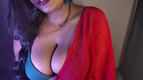 Media: A video of a woman with medium skin tone, wearing a blue bra and a red shawl, showing cleavage, with long dark hair, and wearing a gold necklace.