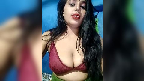 Media: A video of a Latina woman with long black hair, wearing a red lace bra, standing in a pool, blurred background.