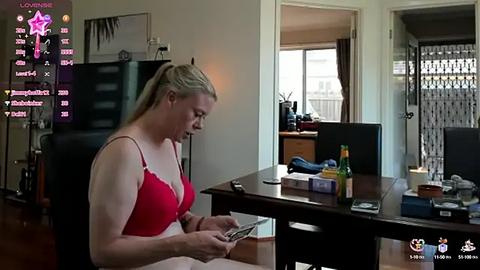 Media: Video of a blonde woman in a red bra, sitting at a desk in a cluttered room, surrounded by computer screens displaying social media icons.