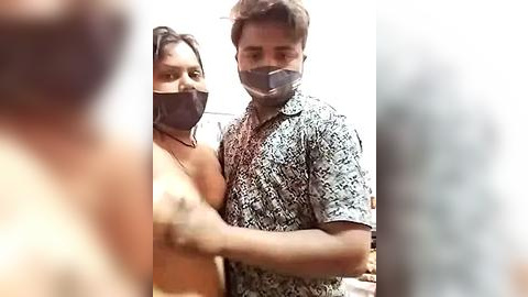 Media: Video of a man in a patterned shirt and a woman in a black mask, with blurred background.