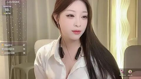 Media: A young Asian woman with long, straight black hair and fair skin, wearing a white shirt, sits indoors, with a soft, wavy lamp in the background.